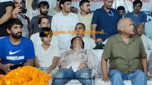 Image showing Indian wrestler Vinesh Phogat looking concerned, possibly due to illness, with a backdrop of a wrestling arena.